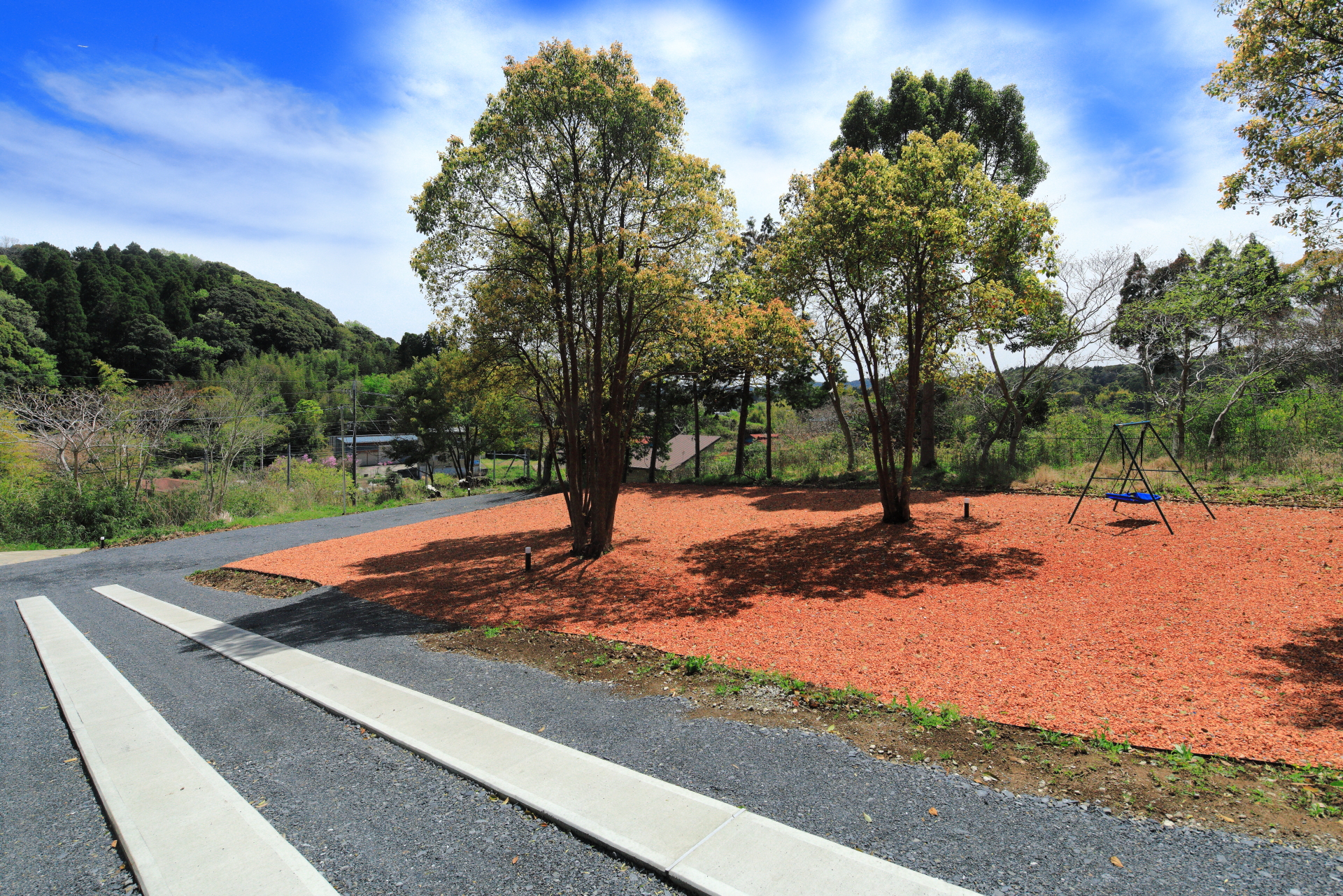 Garden　庭に敷きつめられたレンガチップとVillaのウッド壁の色彩が背景に広がる緑との絶妙なコントラクトが印象的です。