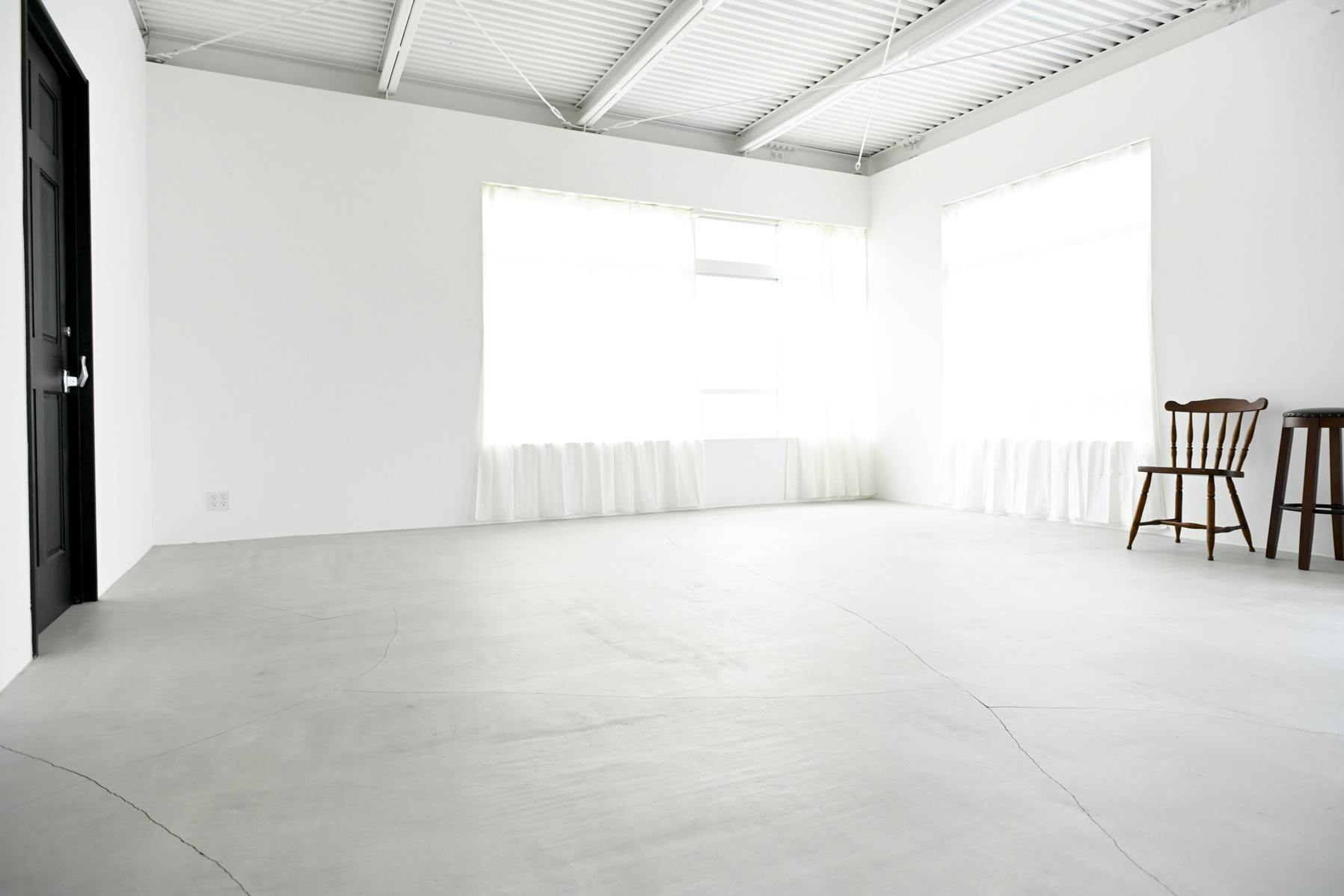 モルタル床のスペースはリネンのレースカーテンで白い窓枠も柔らかい背景に。