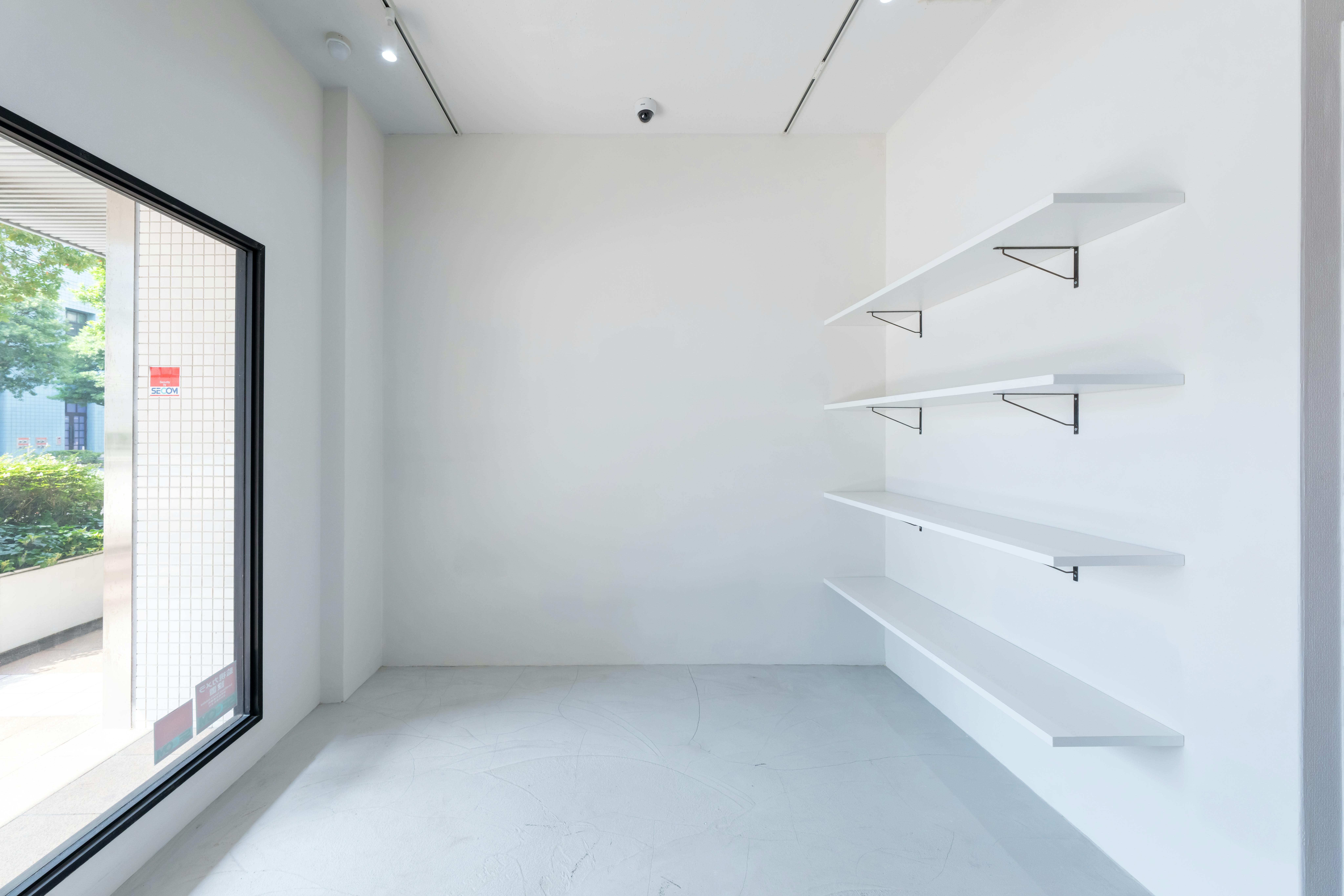 白壁にモルタル床。前面ガラス張りで自然光が入り、撮影利用も可能です。