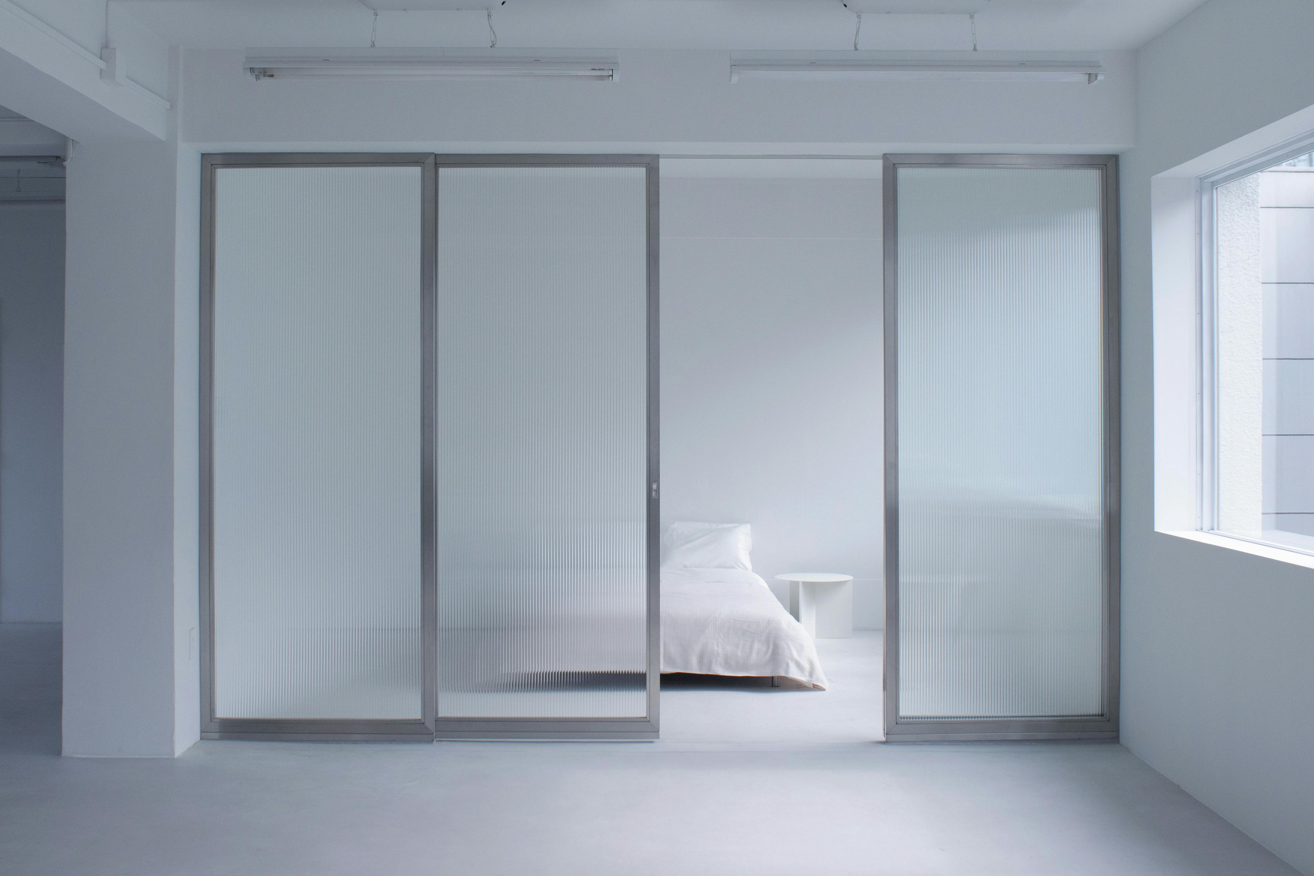 アルミフレームとモールガラスのスライドパーテーションを設置したベッドルーム